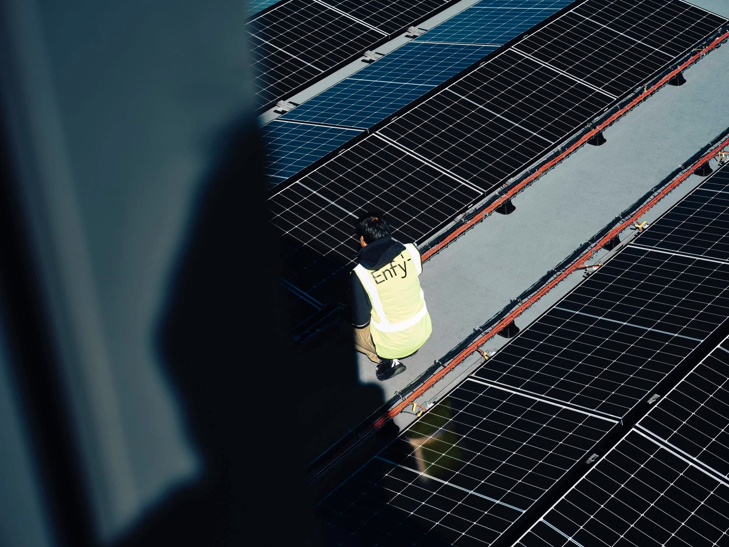 Enfy technician in high-visibility clothing among solar panels